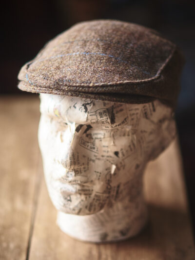A model head wearing a traditional brown flat cap