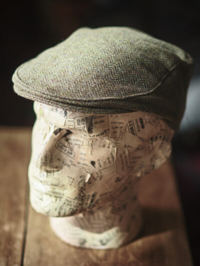 A model head wearing a traditional green flat cap
