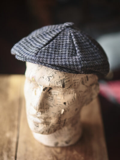 A model head wearing a traditional grey flat cap